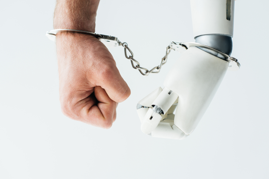 Die Hände eines Menschen und eines Roboters durch eine Handschelle zusammengekettet.